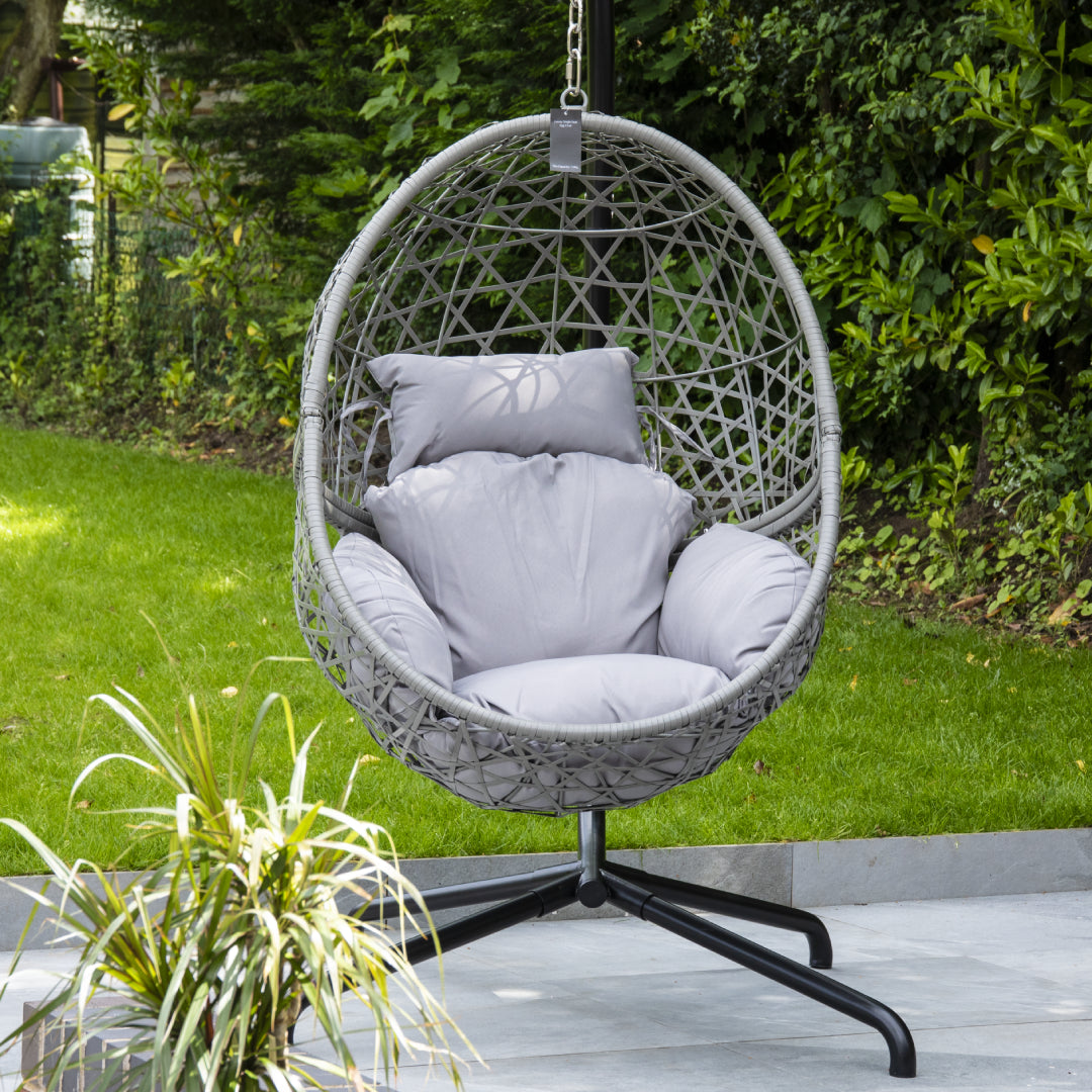 Grey single rattan hanging egg chair with thick cushion on a patio